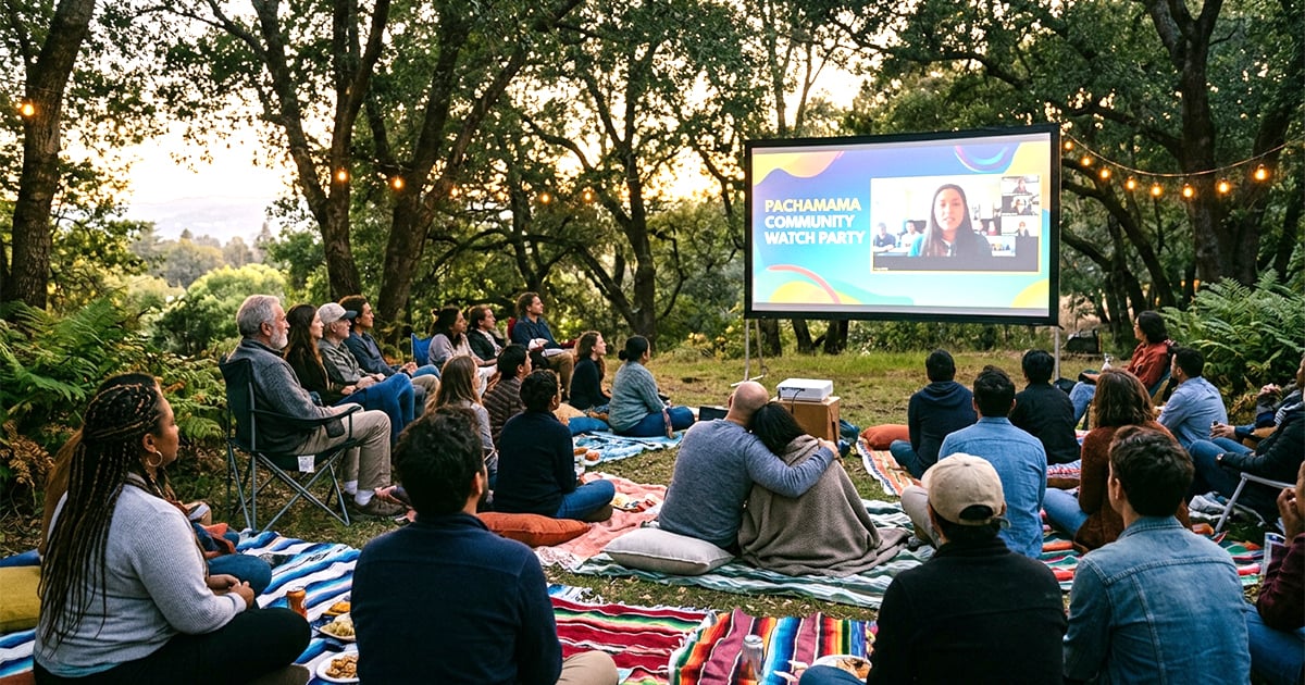 a group of adults gathered outdoors sitting together watching a projected screen